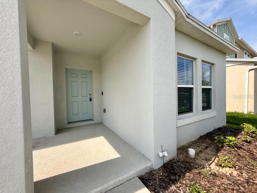 A light blue front door is recessed under a covered porch next to two windows — 870 SAND SEA PLACE, HAINES CITY, FL