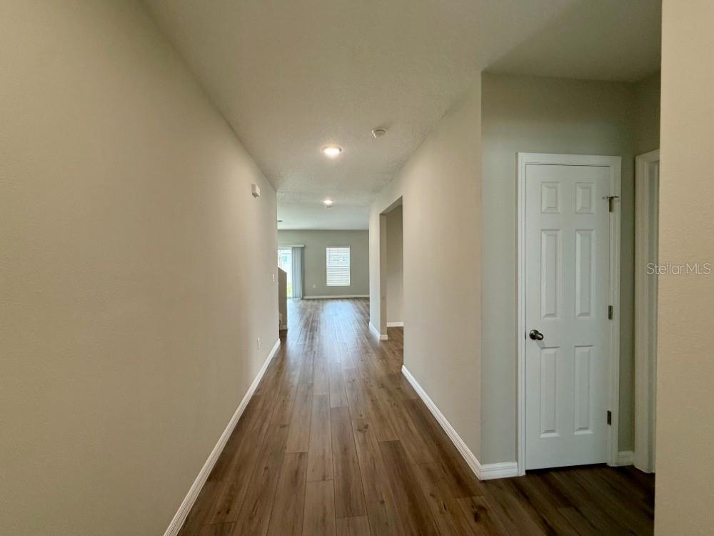 A hallway with wood-look flooring leads toward an open living area with a sliding glass door — 870 SAND SEA PLACE, HAINES CITY, FL