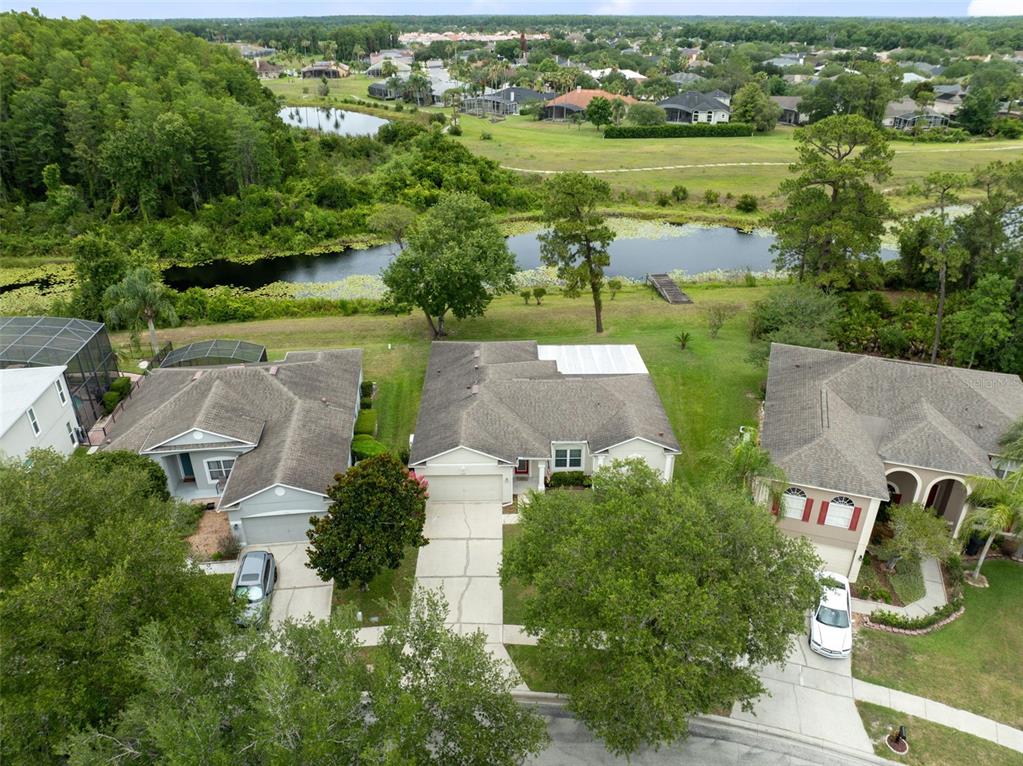 An aerial view shows three suburban houses with driveways facing a pond and green space — 2144 STONE CROSS CIRCLE, ORLANDO, FL