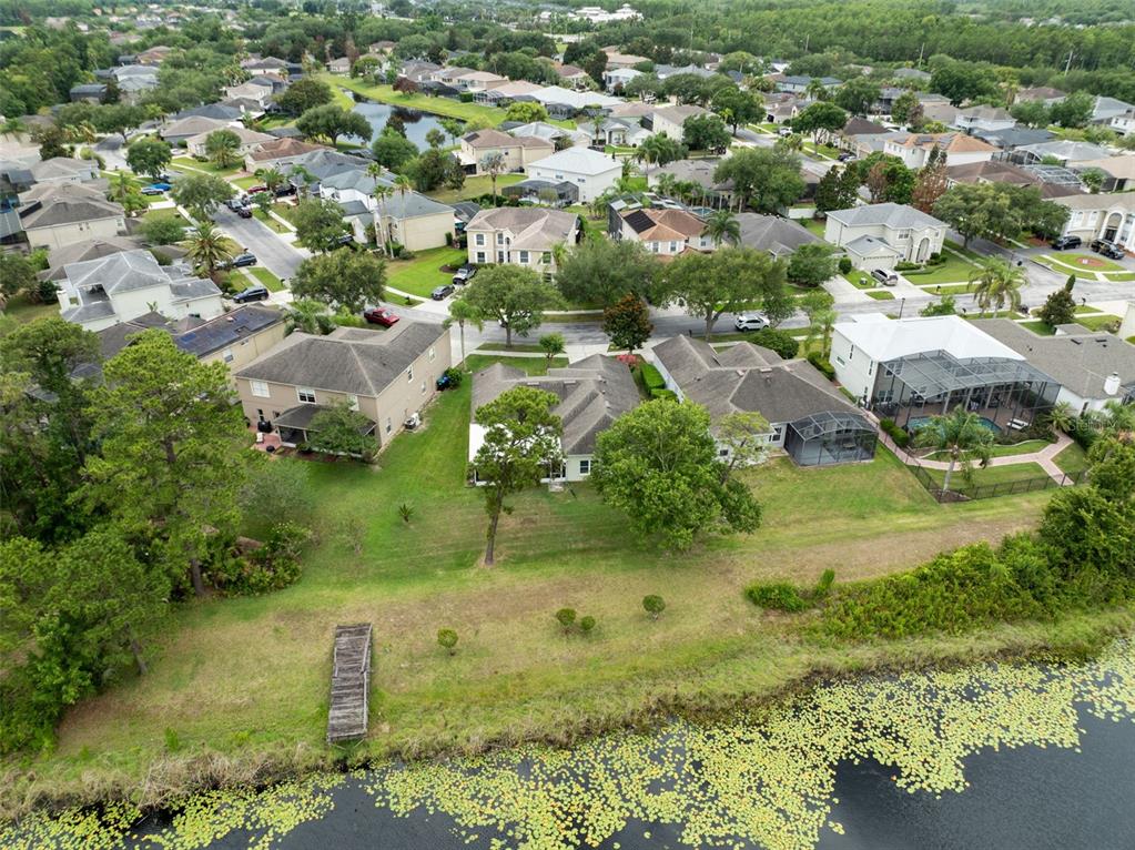An aerial view shows a suburban neighborhood with houses, green lawns, and a pond — 2144 STONE CROSS CIRCLE, ORLANDO, FL