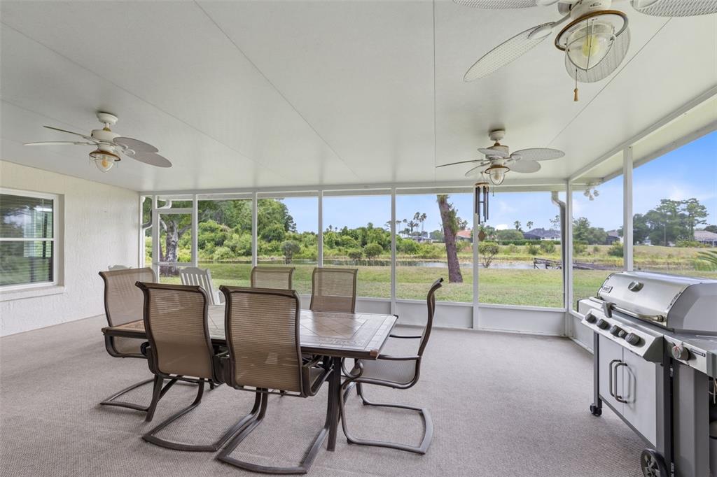 A screened-in patio features a dining set, a grill, and views of a pond — 2144 STONE CROSS CIRCLE, ORLANDO, FL