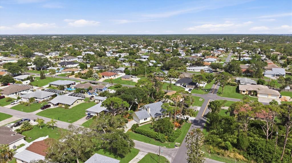 An aerial view of a suburban neighborhood featuring single-family homes, green lawns, and paved streets — 4821 EGRET ROAD, VENICE, FL