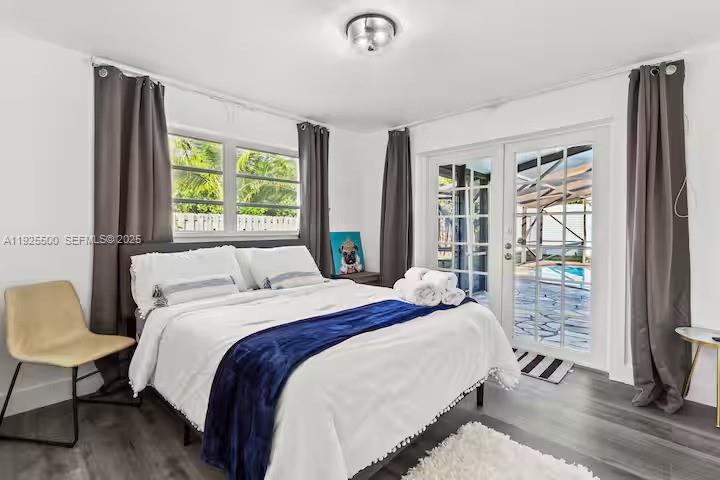 A bedroom features a bed with a blue throw, gray curtains, and glass patio doors — 909 NE 7th St, Pompano Beach FL 33060, POMPANO BEACH, FL