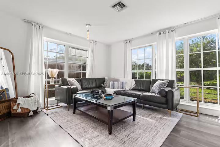 A living room features a dark leather sectional sofa, a glass coffee table, and large windows — 909 NE 7th St, Pompano Beach FL 33060, POMPANO BEACH, FL