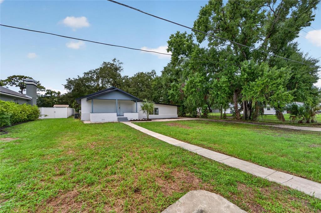 A single-story house with a covered front porch sits on a grassy lot with trees — 8809 DYER ROAD, RIVERVIEW, FL