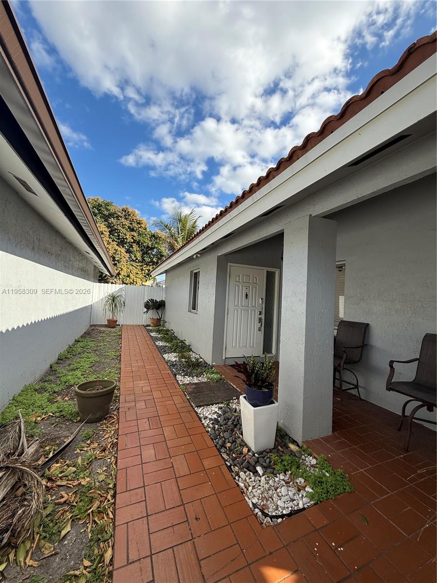 A brick walkway leads to the front entrance of a house with a covered porch — 18237 NW 61st Pl, Hialeah FL 33015, HIALEAH, FL