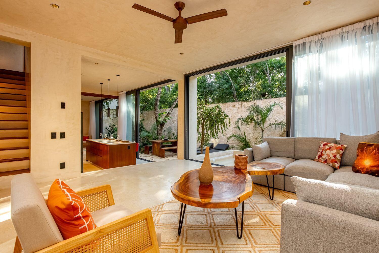 A modern living room with a live-edge coffee table, gray sofa, and large sliding doors — Amari Tulum 10 Avenida Norte & Calle Palma, FL