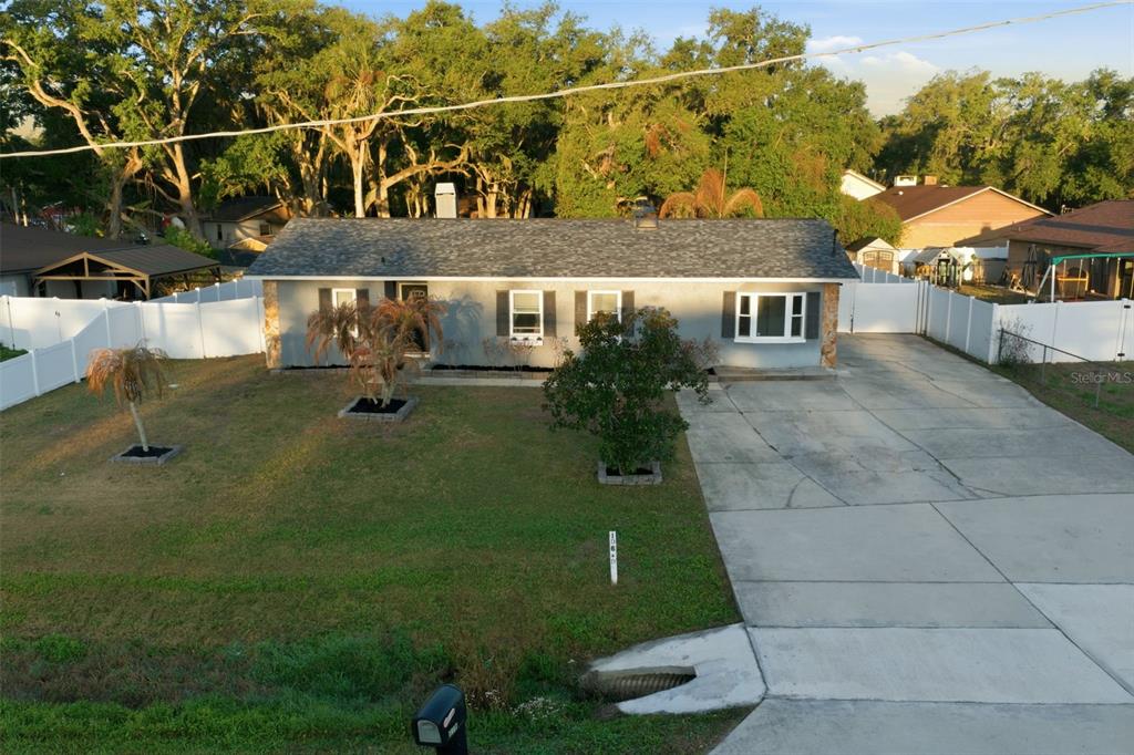 An aerial view of a single-story house with a gray exterior, shingled roof, and driveway — 7403 PROVIDENCE ROAD, RIVERVIEW, FL