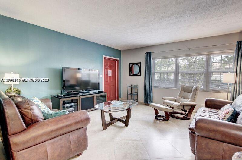 A living room features brown leather furniture, a glass coffee table, and a teal accent wall — 221 SE 9th Ave # 112, Pompano Beach FL 33060, POMPANO BEACH, FL