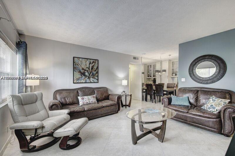 A living room features two brown leather sofas, a light-colored recliner, and tile flooring — 221 SE 9th Ave # 112, Pompano Beach FL 33060, POMPANO BEACH, FL