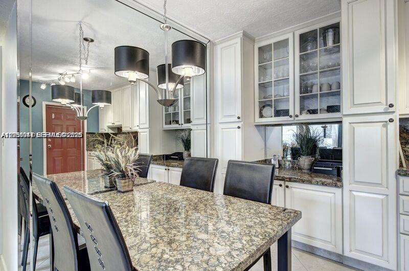 A dining area features a granite-topped table, black chairs, and a large wall mirror — 221 SE 9th Ave # 112, Pompano Beach FL 33060, POMPANO BEACH, FL