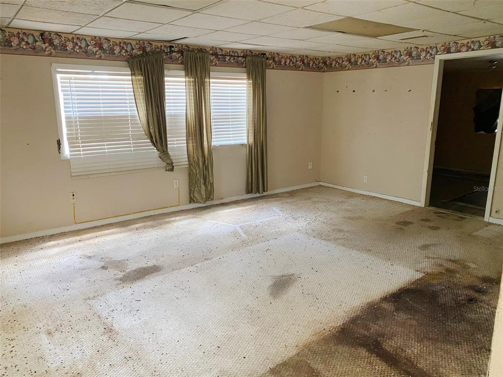 A room with tiled flooring, a drop ceiling, floral wallpaper border, and an open doorway — 3213 E DIANA STREET, TAMPA, FL