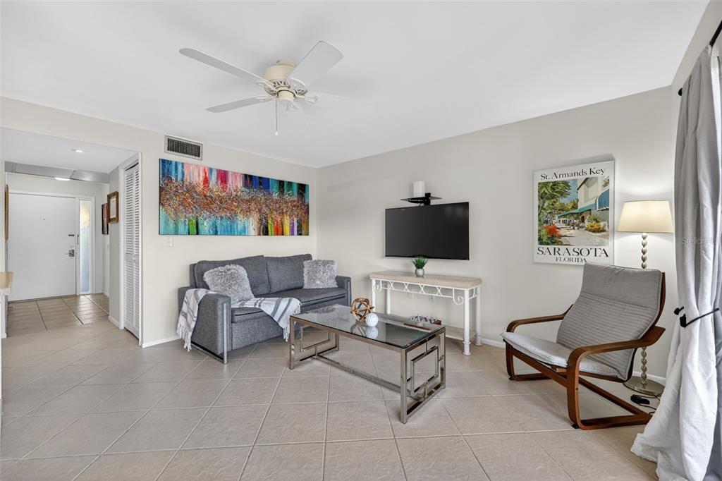 A living room features a gray sofa, glass coffee table, armchair, and wall-mounted television — 3061 QUAIL HOLLOW UNIT # 35, SARASOTA, FL