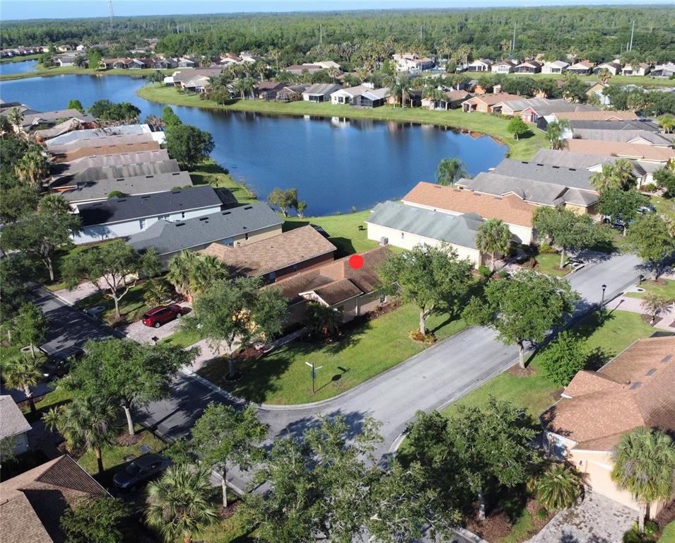 An aerial view shows a residential neighborhood with houses surrounding a central lake — 537 GRAND CANAL DRIVE, POINCIANA, FL