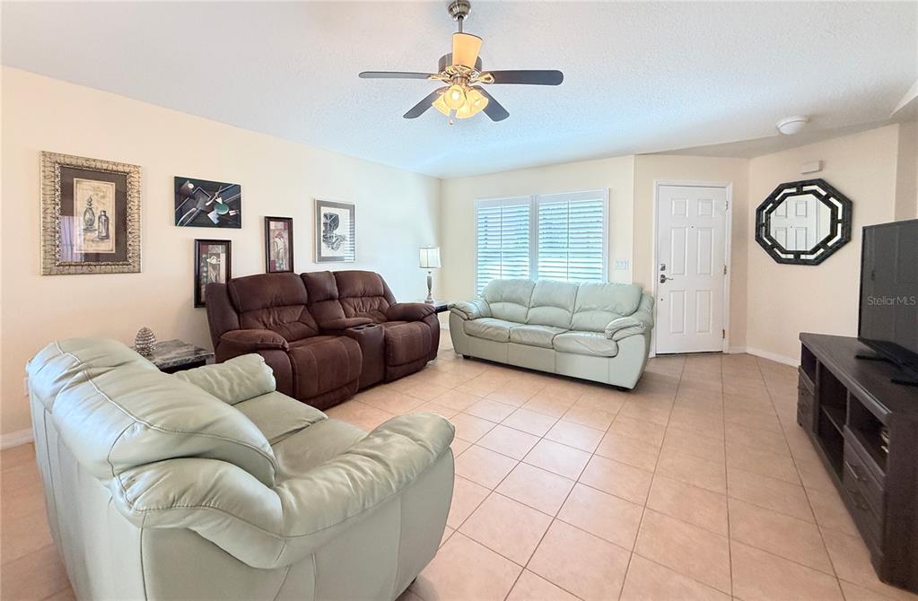 A living room features tile flooring, a ceiling fan, and three leather sofas — 537 GRAND CANAL DRIVE, POINCIANA, FL
