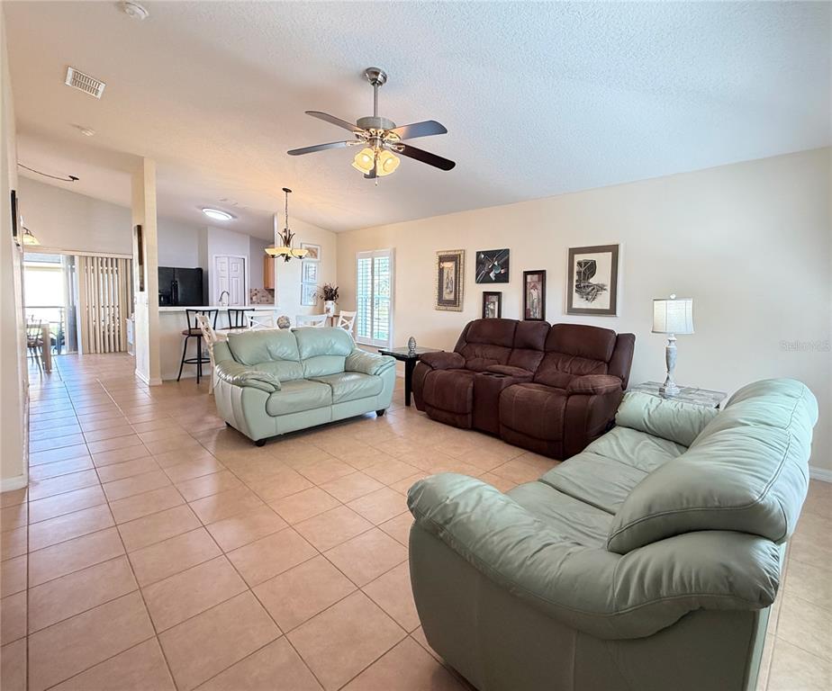 A living room features tile floors, two light green sofas, and a brown reclining sofa — 537 GRAND CANAL DRIVE, POINCIANA, FL