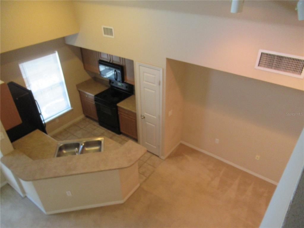 An elevated view shows a kitchen with dark appliances, wood cabinets, and a breakfast bar — 5601 ROSEHILL ROAD UNIT 203, SARASOTA, FL