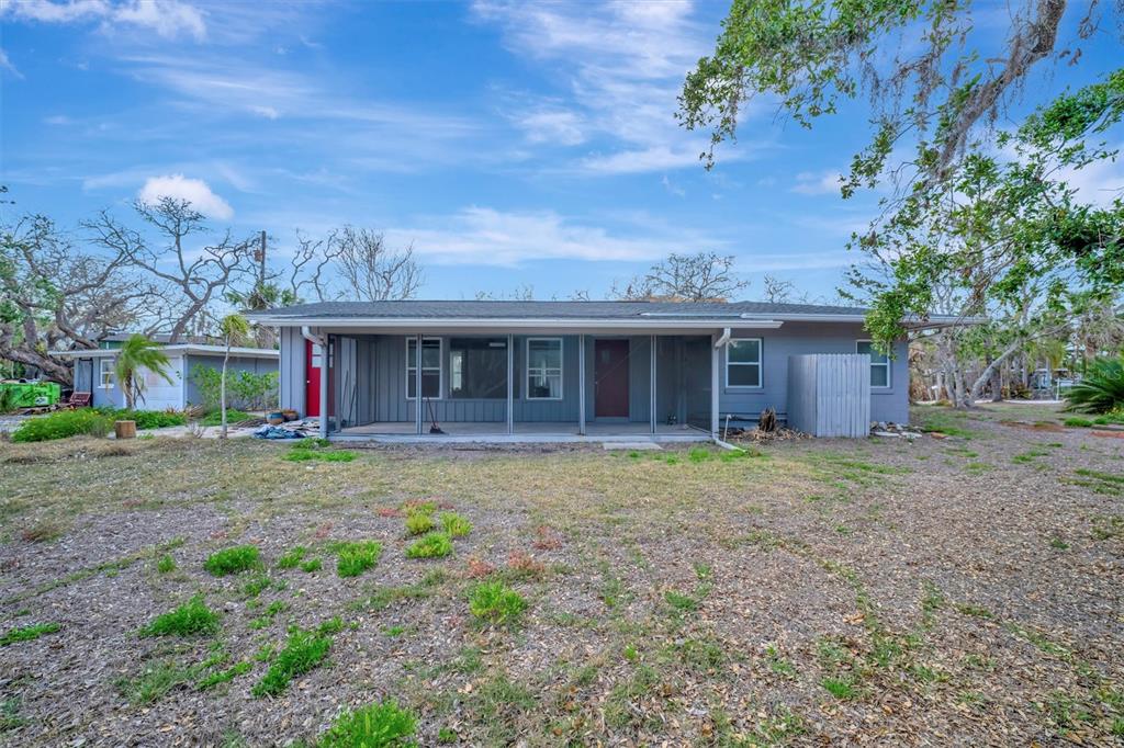 The exterior of a gray single-story house features a screened-in porch and a large yard — 8555 HERON LAGOON CIRCLE, SARASOTA, FL