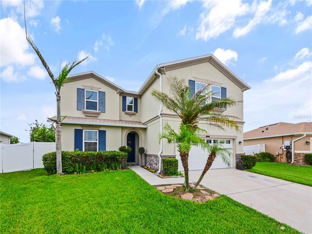 A two-story suburban house with a beige stucco exterior, blue shutters, and a front lawn — 4597 BALER TRAILS DRIVE, ST CLOUD, FL
