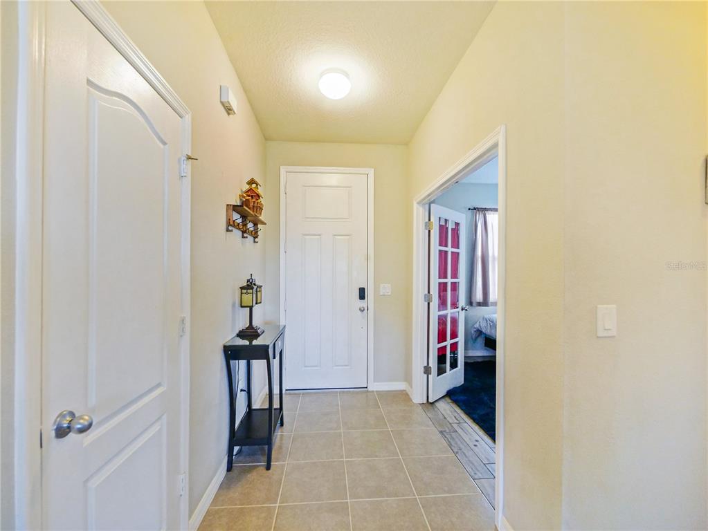 A tiled entryway features a white front door, a side table, and an adjacent room — 4597 BALER TRAILS DRIVE, ST CLOUD, FL