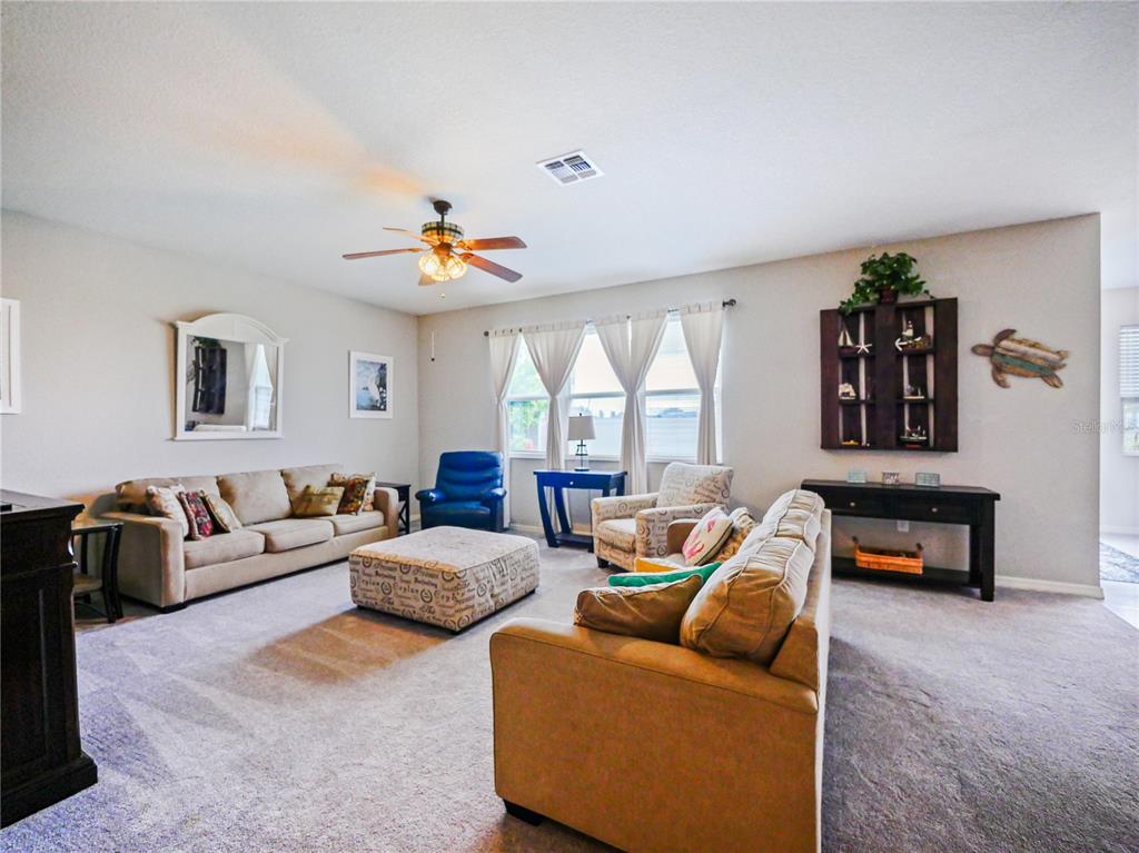 A living room features two beige sofas, a patterned ottoman, and a blue recliner — 4597 BALER TRAILS DRIVE, ST CLOUD, FL