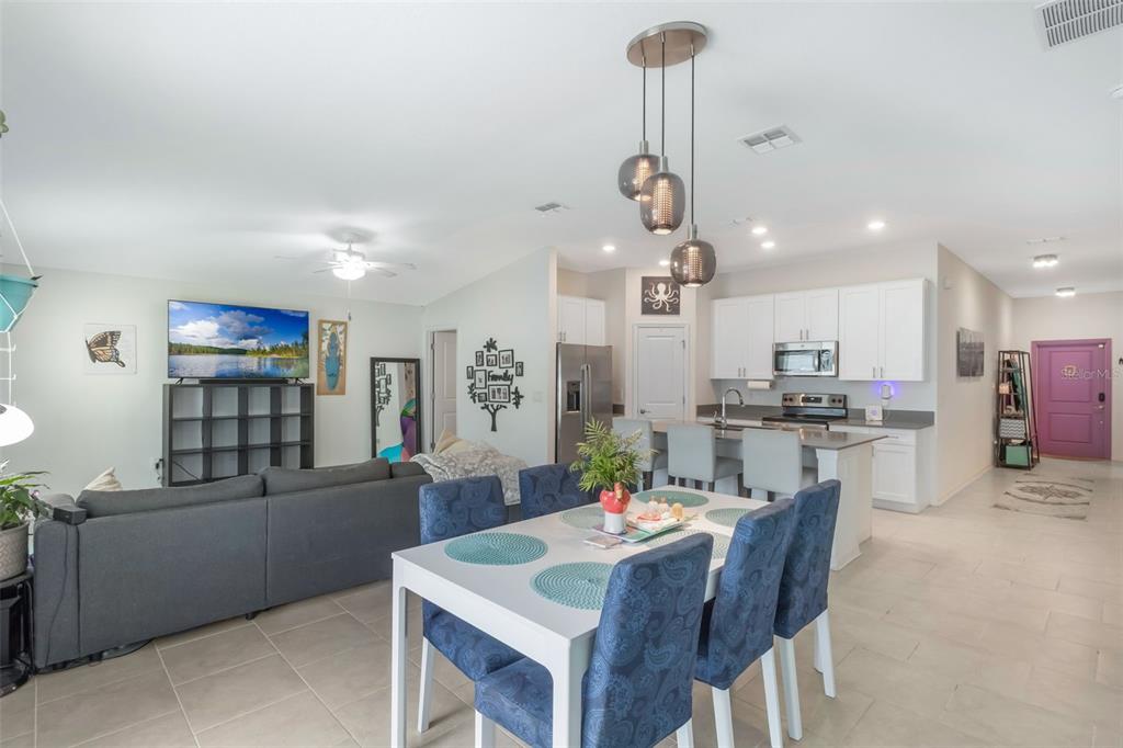 An open-concept living room and kitchen featuring a dining table, gray sofa, and white cabinets — 621 SILVER PALM DRIVE, HAINES CITY, FL