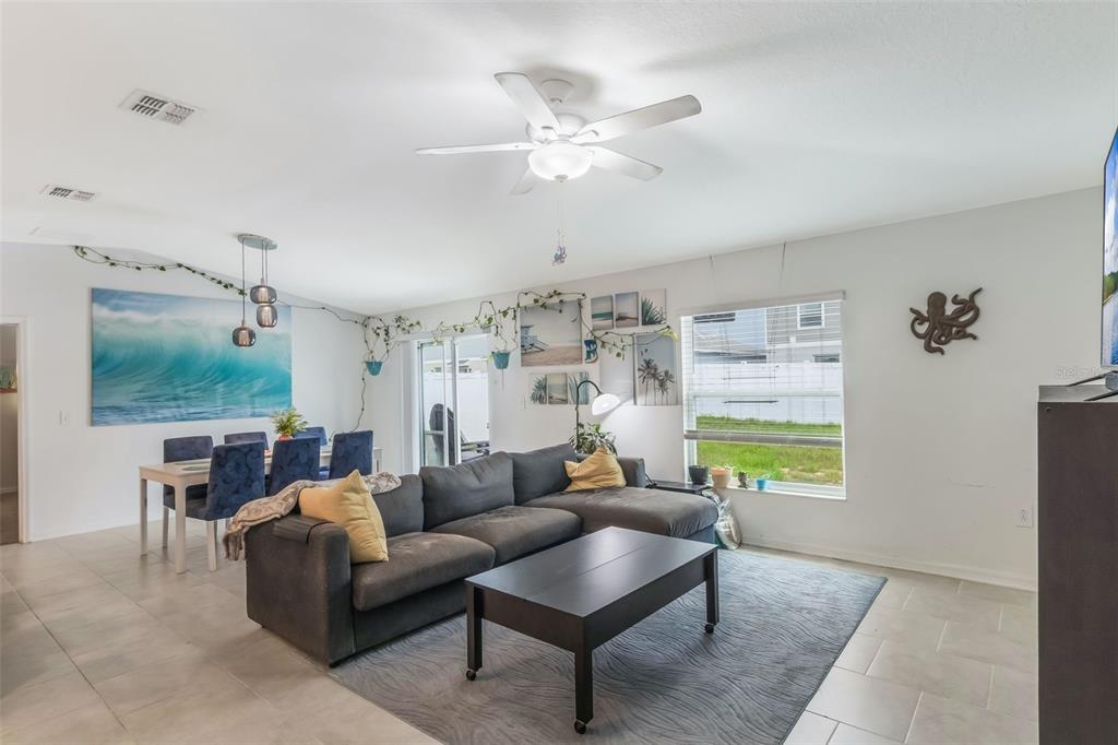 A living room with a gray sectional sofa, coffee table, dining area, and ceiling fan — 621 SILVER PALM DRIVE, HAINES CITY, FL