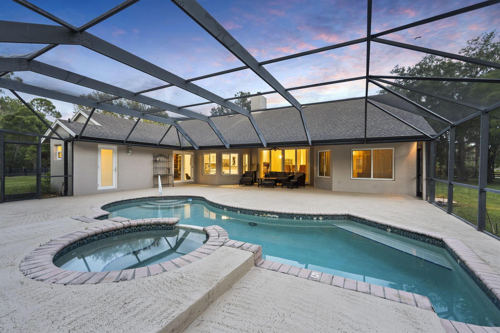 A screened-in patio features a swimming pool and attached hot tub behind a house — 17225 Mare Lane, Loxahatchee FL 33470, LOXAHATCHEE, FL