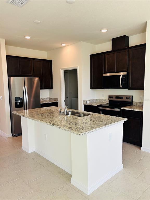 A kitchen features dark wood cabinets, granite countertops, a center island, and stainless steel appliances — 2318 SELENIA STREET, LAKE ALFRED, FL