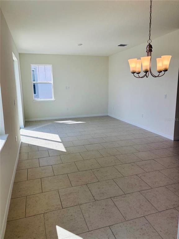 A dining area with light-colored tile flooring, a chandelier, and a single window — 2318 SELENIA STREET, LAKE ALFRED, FL