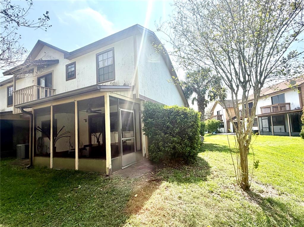 A two-story house with a screened-in porch and a balcony sits on a grassy lawn — 2139 BALBOA WAY, KISSIMMEE, FL
