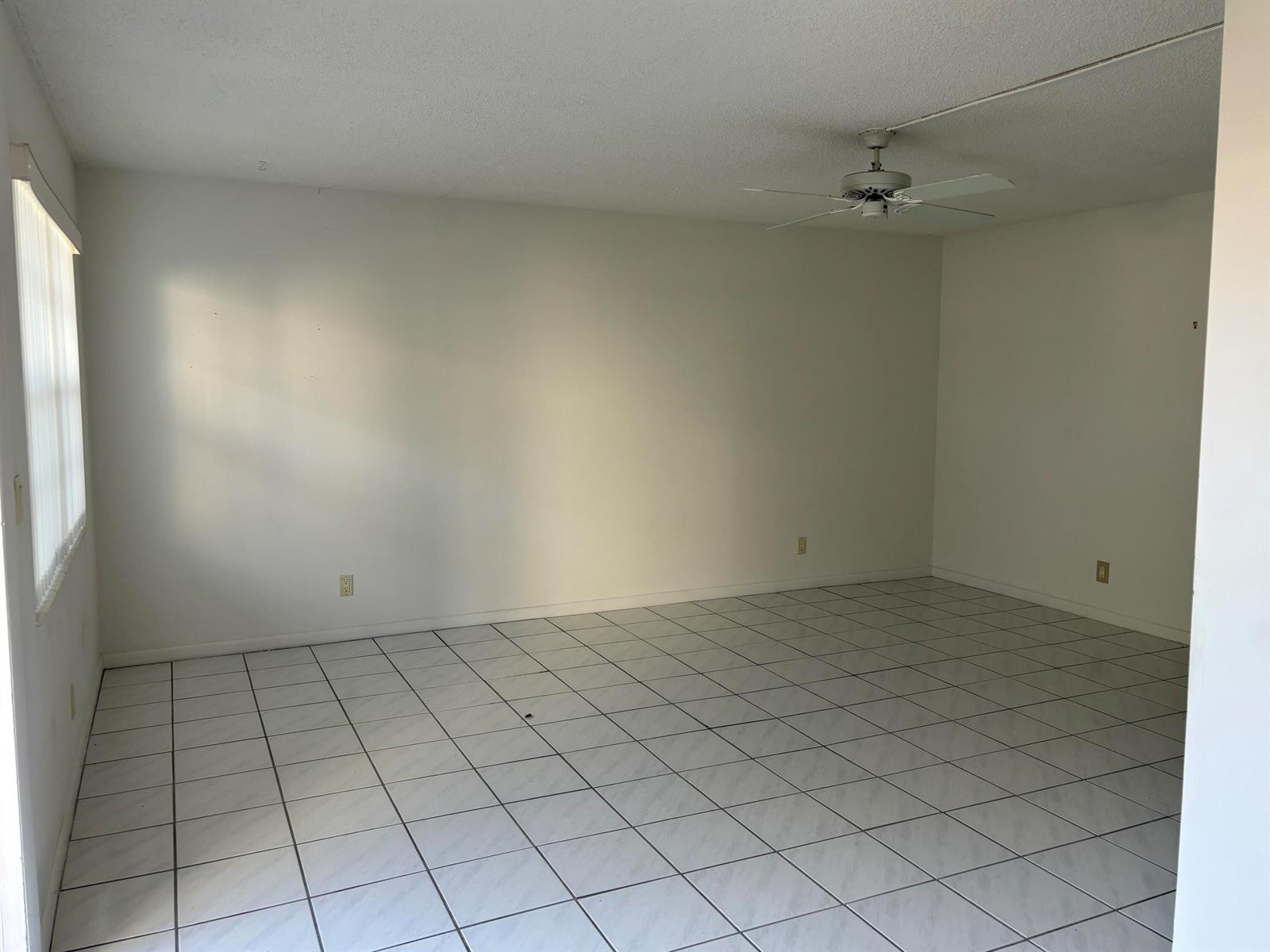 An empty room with white walls, white tile flooring, and a ceiling fan — 75 Sheffield D, West Palm Beach FL 33417, WEST PALM BEACH, FL