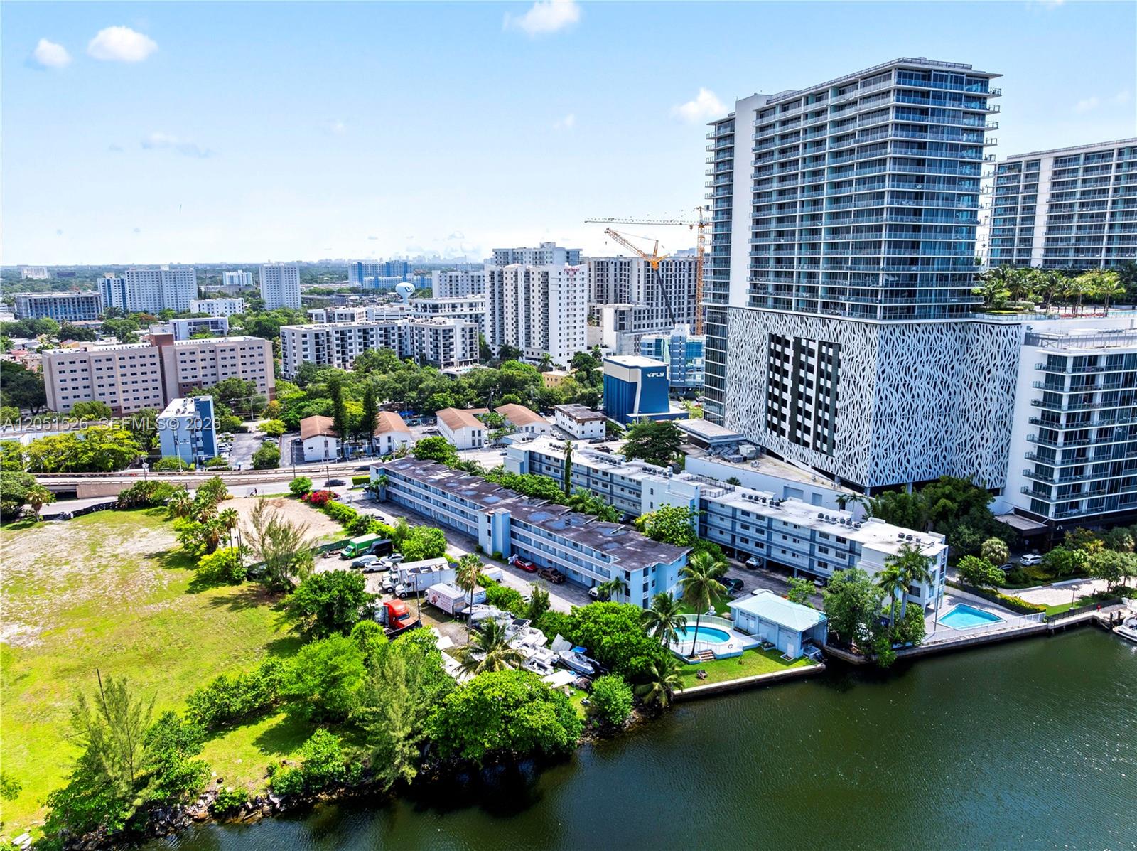 An aerial view shows a multi-story apartment complex with a pool beside a canal — 1610 NW N River Dr # 201, Miami FL 33125, MIAMI, FL
