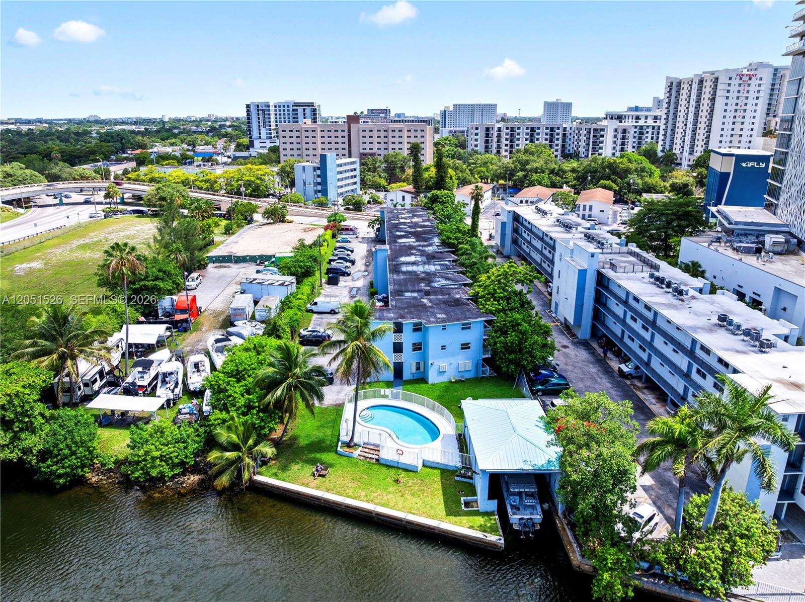 An aerial view shows a blue apartment complex with a pool and boat slip — 1610 NW N River Dr # 201, Miami FL 33125, MIAMI, FL