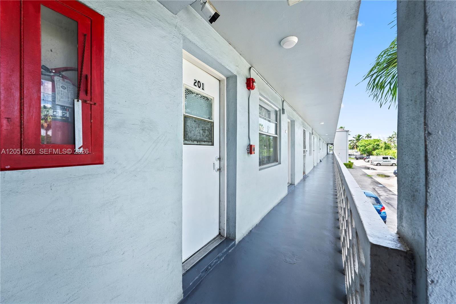 An exterior walkway leads past apartment door 201, featuring a red fire extinguisher cabinet — 1610 NW N River Dr # 201, Miami FL 33125, MIAMI, FL