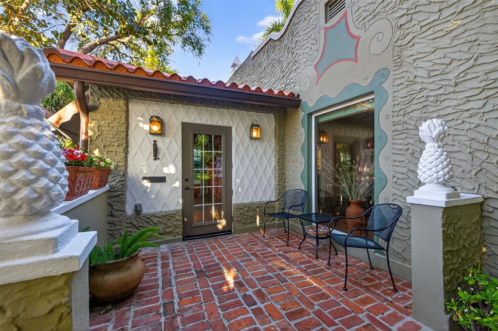 A brick patio features two metal chairs, a small table, and pineapple-shaped statues — 745 16TH AVENUE NE, ST PETERSBURG, FL