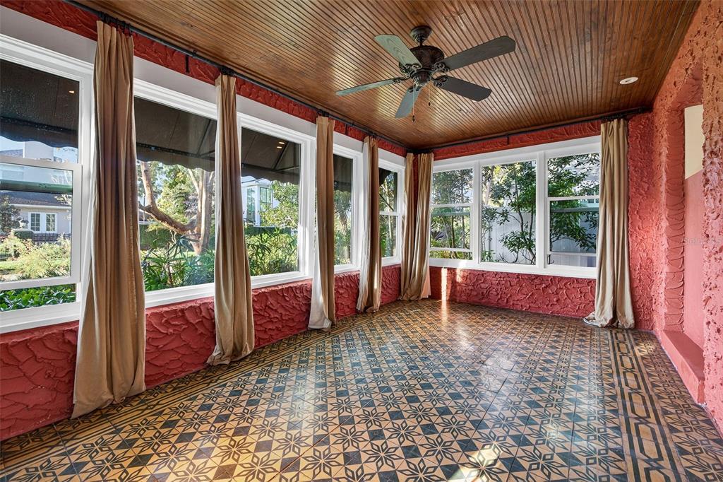 A sunroom features a patterned tile floor, red textured walls, and a wood-paneled ceiling — 745 16TH AVENUE NE, ST PETERSBURG, FL