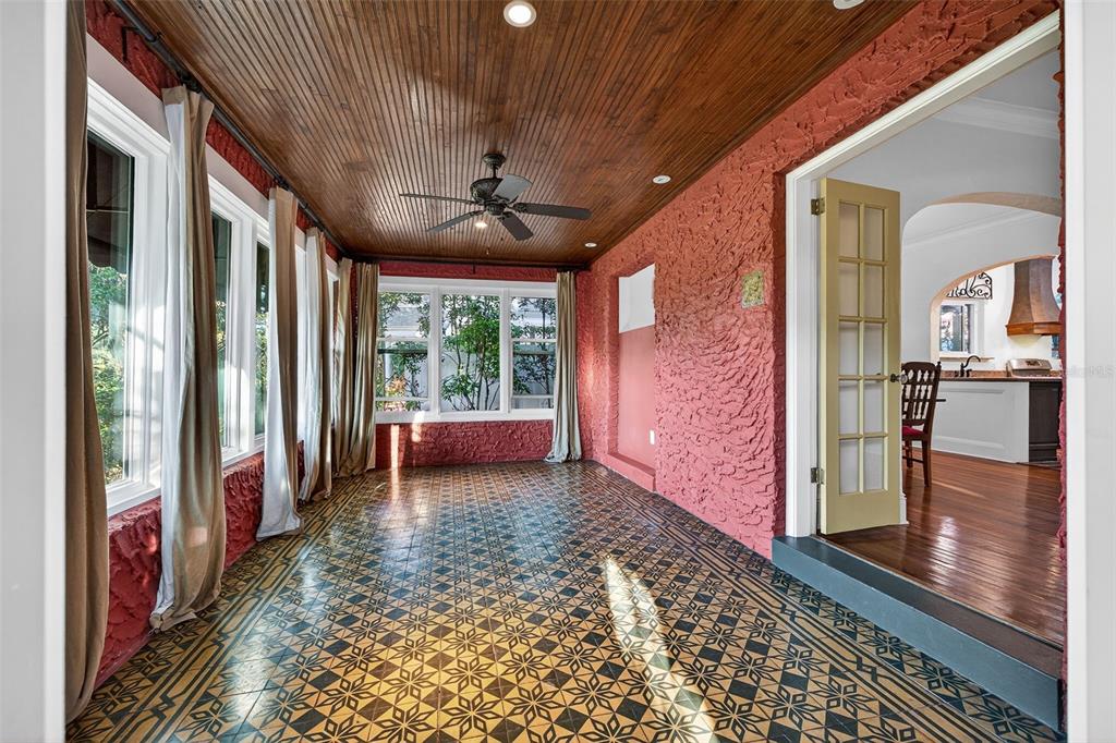 A sunroom with a wood-paneled ceiling, patterned tile floor, and textured red walls — 745 16TH AVENUE NE, ST PETERSBURG, FL
