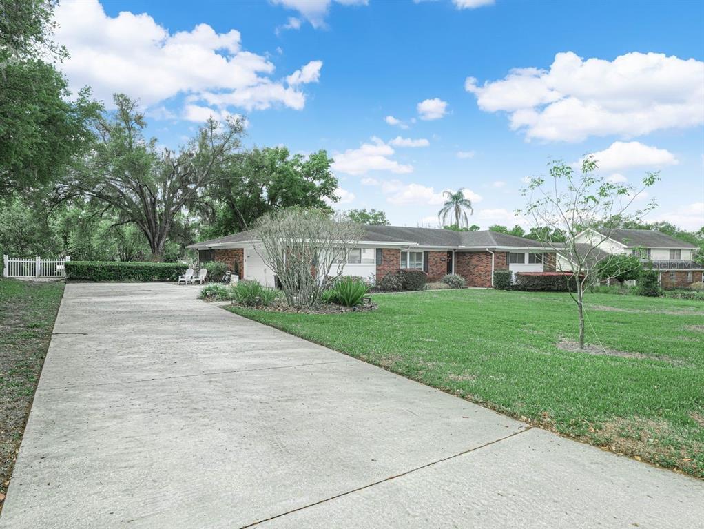 A single-story brick house with a long concrete driveway and a large front lawn — 1709 VIRGINIA COURT, LAKELAND, FL