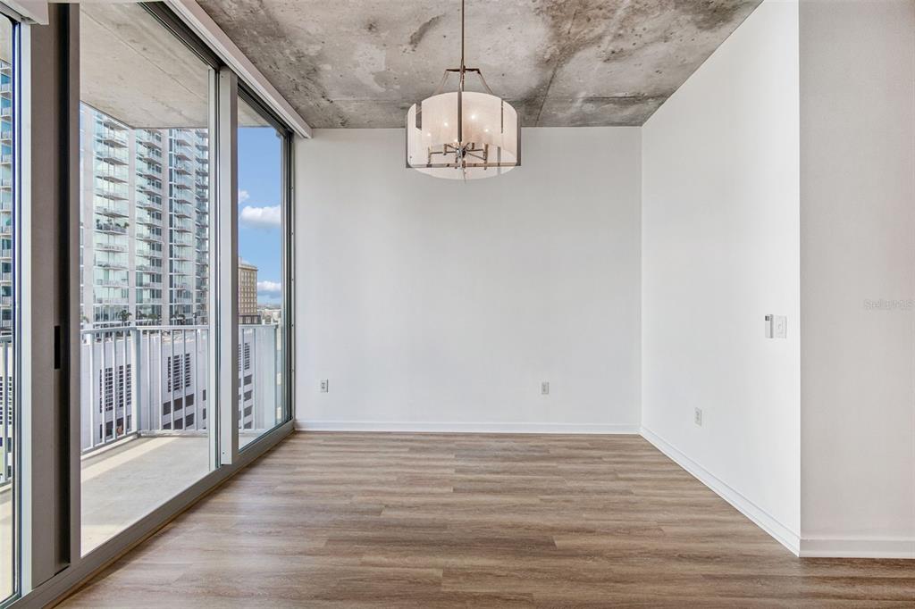 An empty dining area features a concrete ceiling, wood-look flooring, and a balcony with views — 777 N ASHLEY DRIVE UNIT 1213, TAMPA, FL