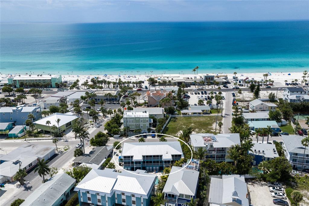 An aerial view shows a multi-story building with a white roof near the beach — 205 HIGHLAND AVENUE UNIT 2, BRADENTON BEACH, FL
