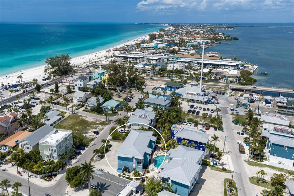 An aerial view shows a blue multi-story house with a pool in a coastal neighborhood — 205 HIGHLAND AVENUE UNIT 2, BRADENTON BEACH, FL