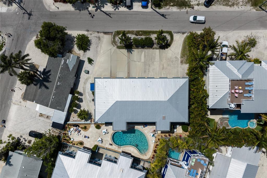 An aerial view shows a house with a metal roof, a pool, and a driveway — 205 HIGHLAND AVENUE UNIT 2, BRADENTON BEACH, FL