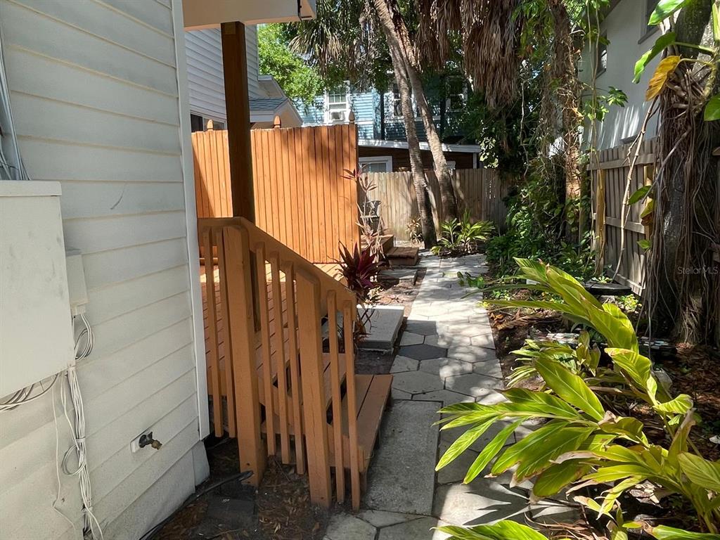 A wooden staircase leads to a deck beside a stone path in a backyard — 255 6TH AVENUE N UNIT 3, ST PETERSBURG, FL