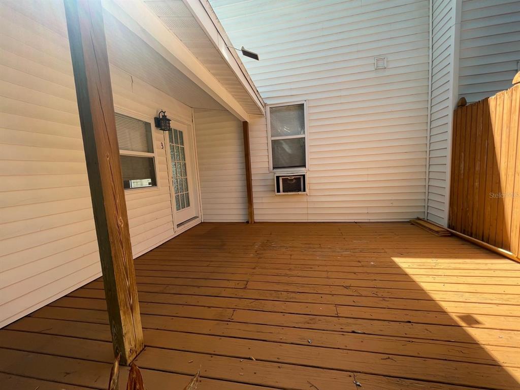 A wooden deck sits outside a house with white siding, a door, and a window — 255 6TH AVENUE N UNIT 3, ST PETERSBURG, FL