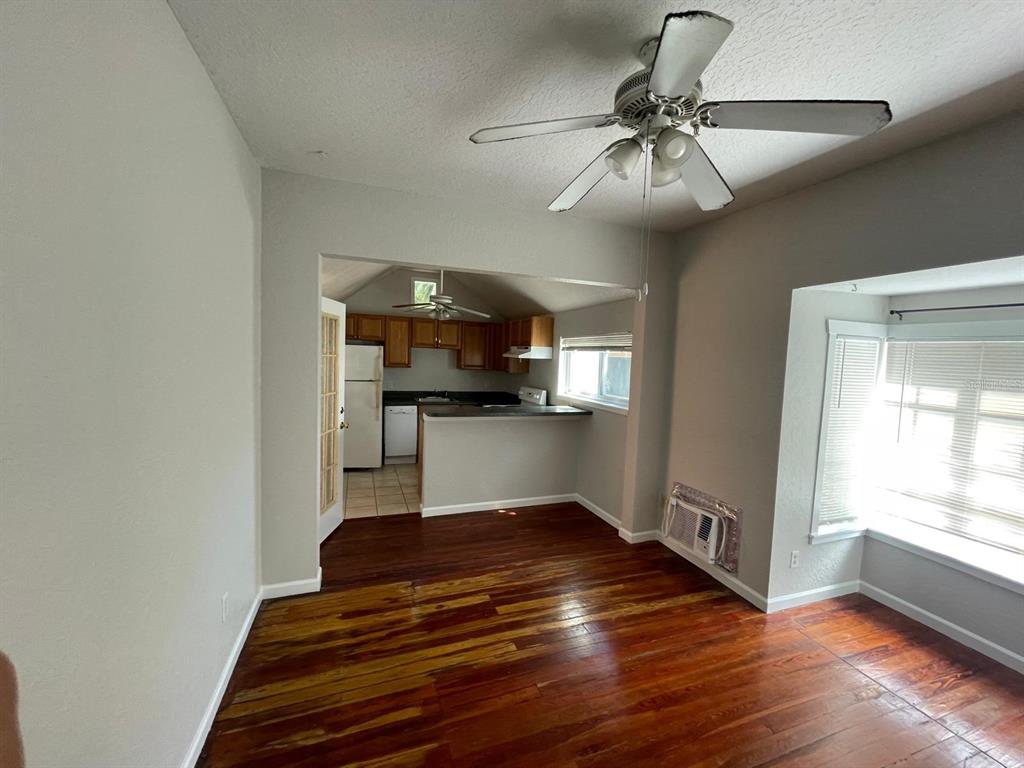 A living area with hardwood floors leads into a kitchen with wooden cabinets and appliances — 255 6TH AVENUE N UNIT 3, ST PETERSBURG, FL