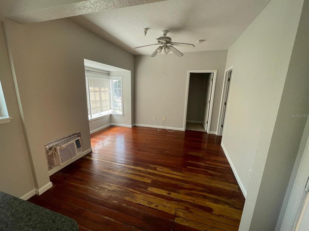 An empty room features hardwood floors, a ceiling fan, and a bay window — 255 6TH AVENUE N UNIT 3, ST PETERSBURG, FL