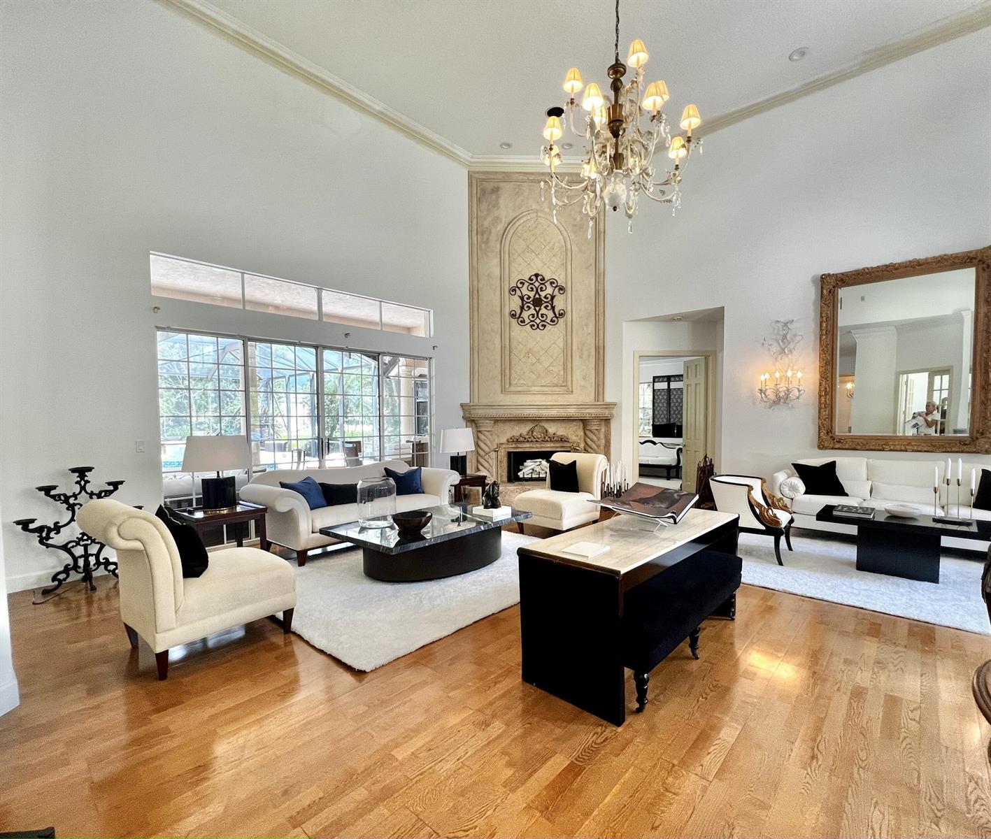 A spacious living room features high ceilings, a stone fireplace, and hardwood floors — 2050 Windsock Way, Wellington FL 33414, WELLINGTON, FL