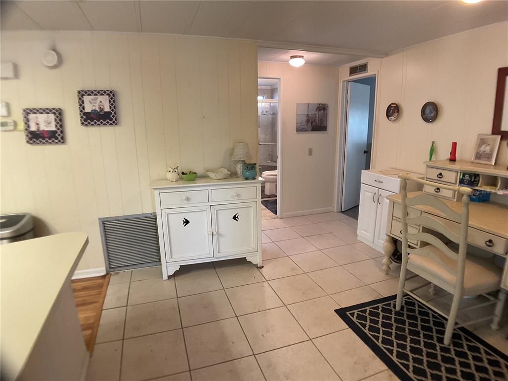 A room with tiled flooring, a white cabinet, a desk, and a doorway leading to a bathroom — 2100 KINGS HIGHWAY UNIT 47, PORT CHARLOTTE, FL