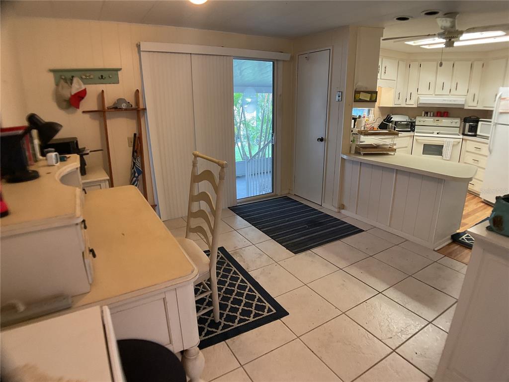 A kitchen and dining area feature white cabinetry, tile flooring, and a sliding glass door — 2100 KINGS HIGHWAY UNIT 47, PORT CHARLOTTE, FL